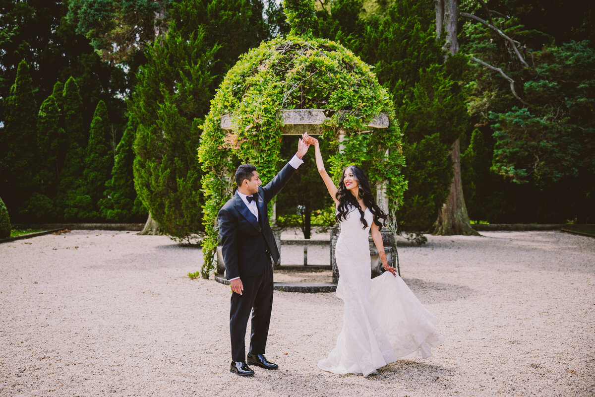Groom twirling the bride in a white dress on their Indian wedding day at oheka castle