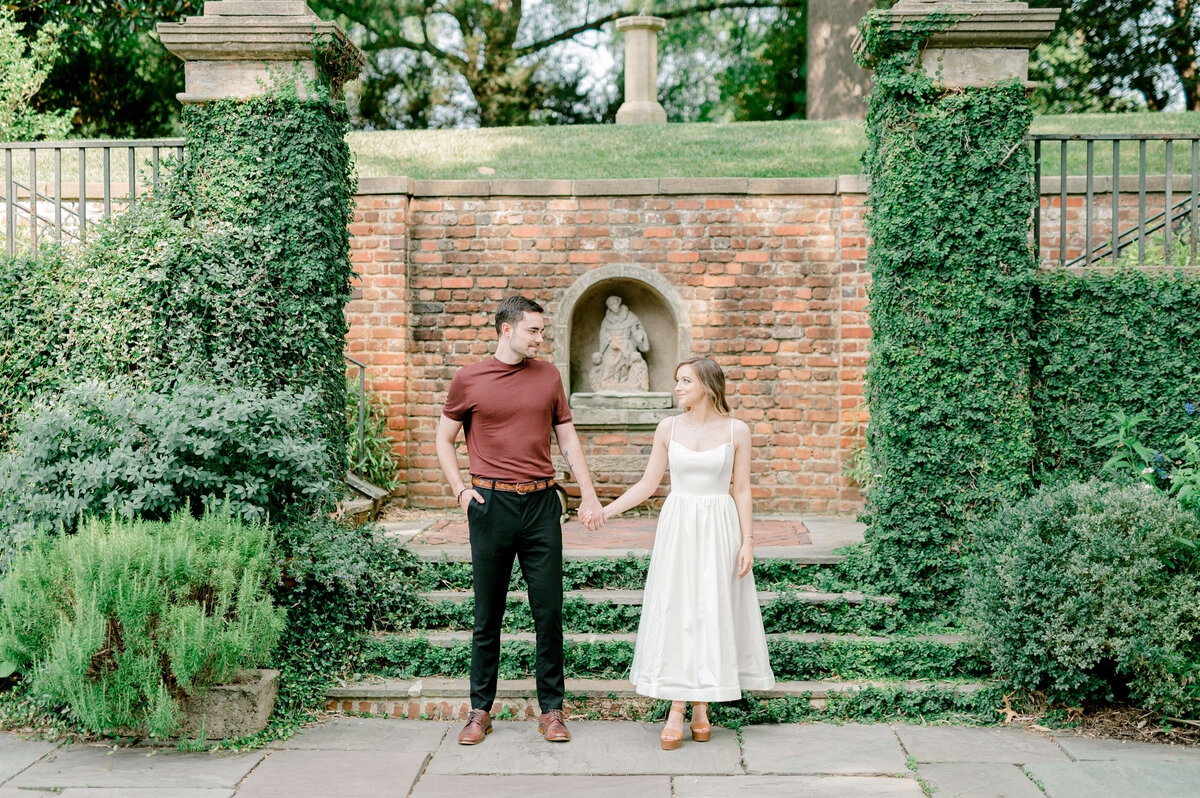 Future bride and groom holding hands in the National Cathedral Gardens during engagement session.