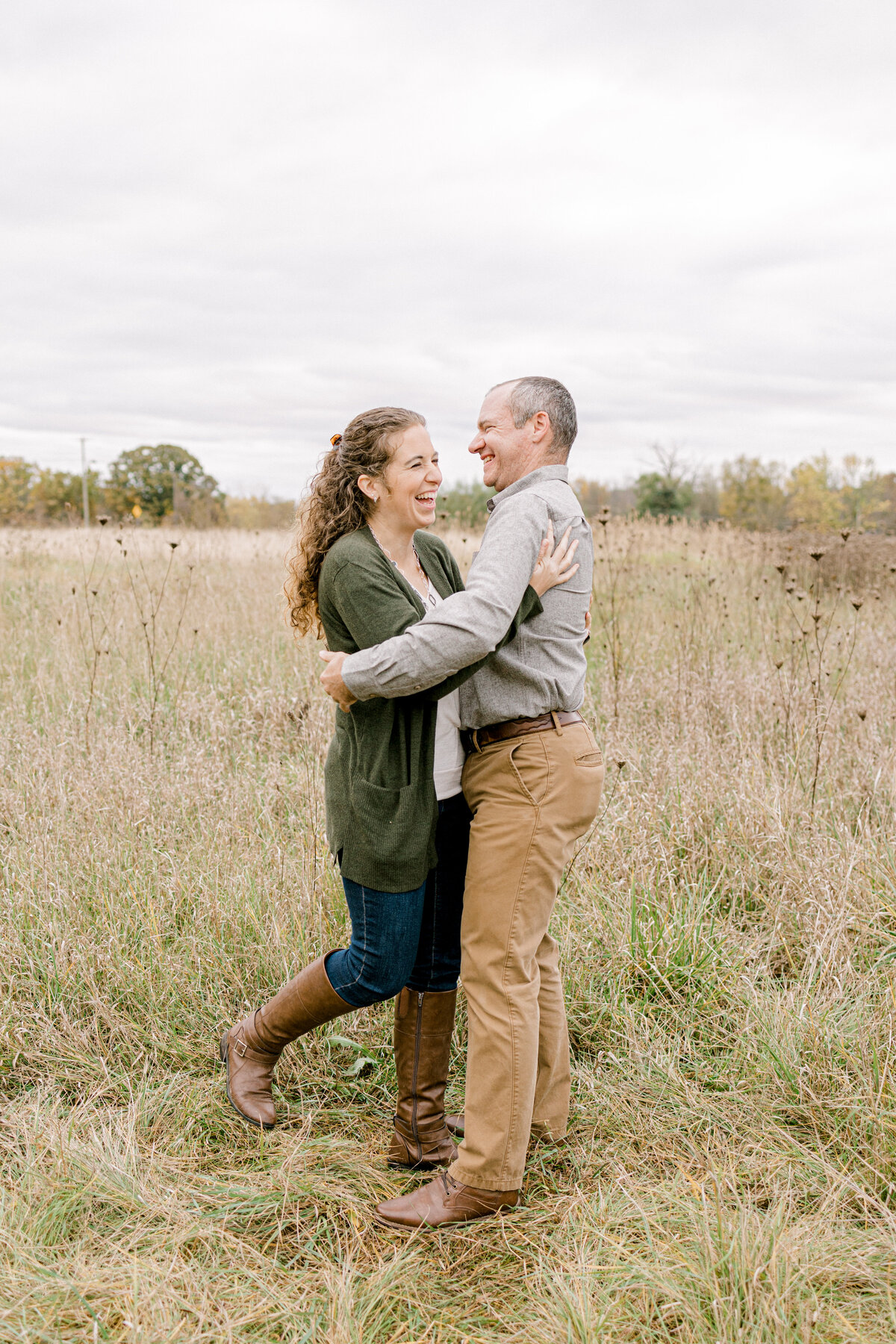 couple facing each other and laughing in a field