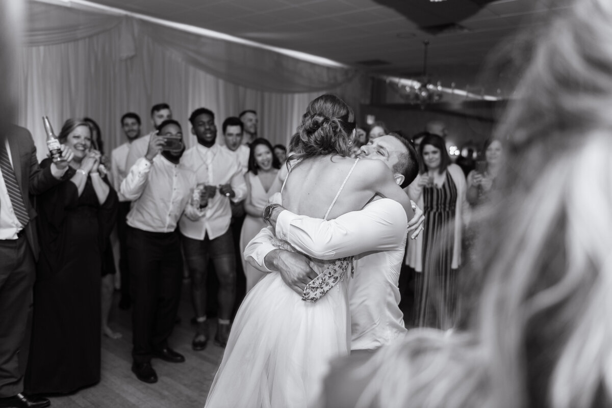 extremely happy couple hug one another in front of all family and guests at their wedding reception. Cleveland, Ohio. Photo taken by Aaron Aldhizer