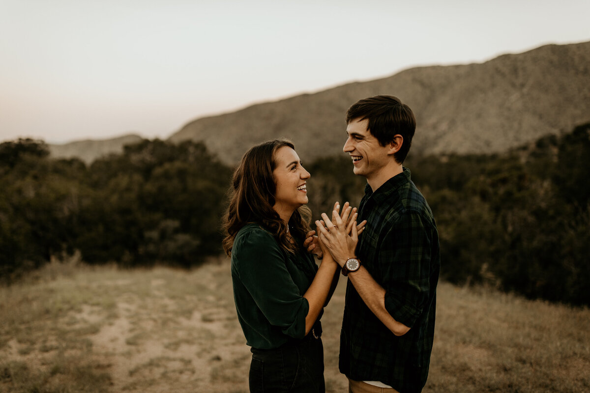 engaged couple holding hands and laughing at the foothills in Albuquerque