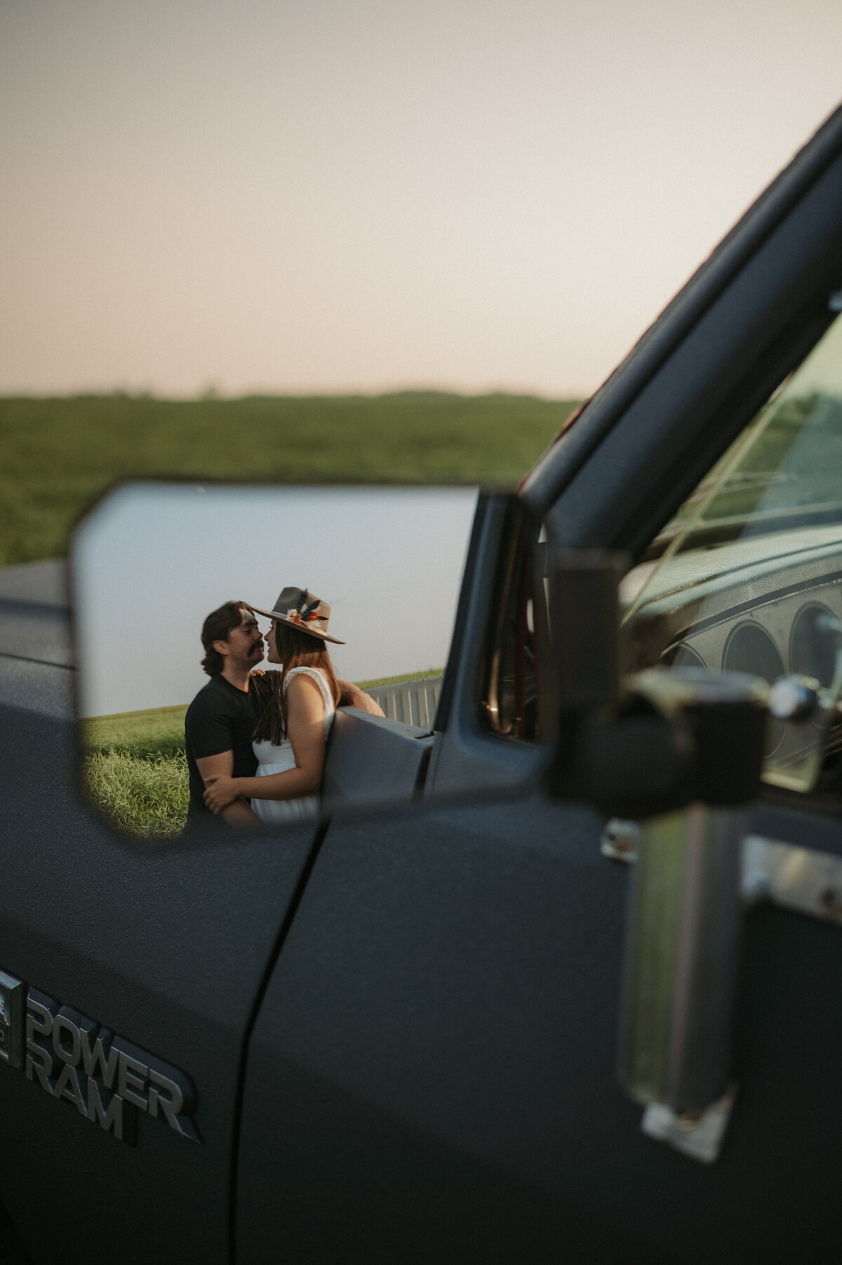 Photo of truck mirror reflecting couple kissing during photoshoot