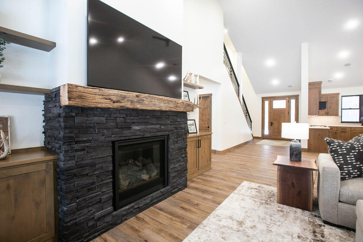 Cozy living room in Elk River custom home with fireplace, built-ins, and large windows