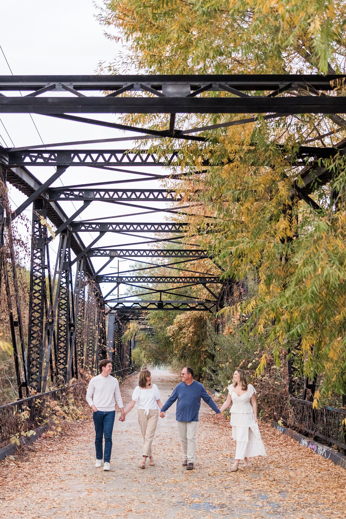 family holding hands and walking on sweetwater river bridge