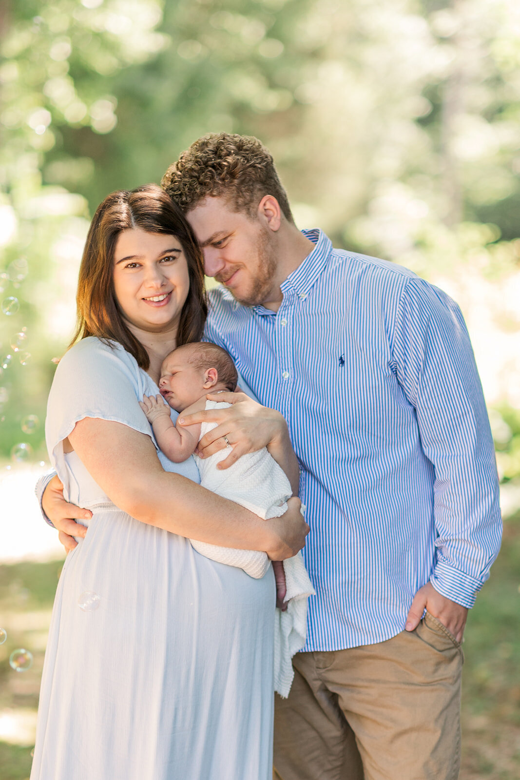 Parents cradling baby during intimate in-home portrait session