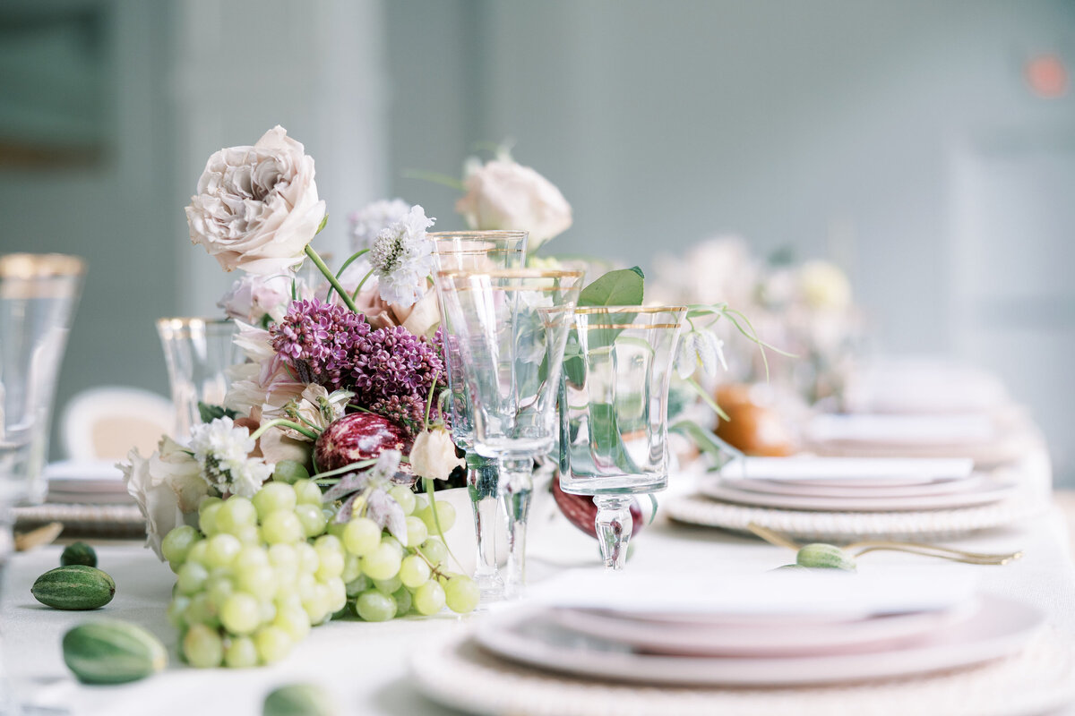 Pastel florals with grapes and gold-rimmed glassware on an elegant Houston reception table.