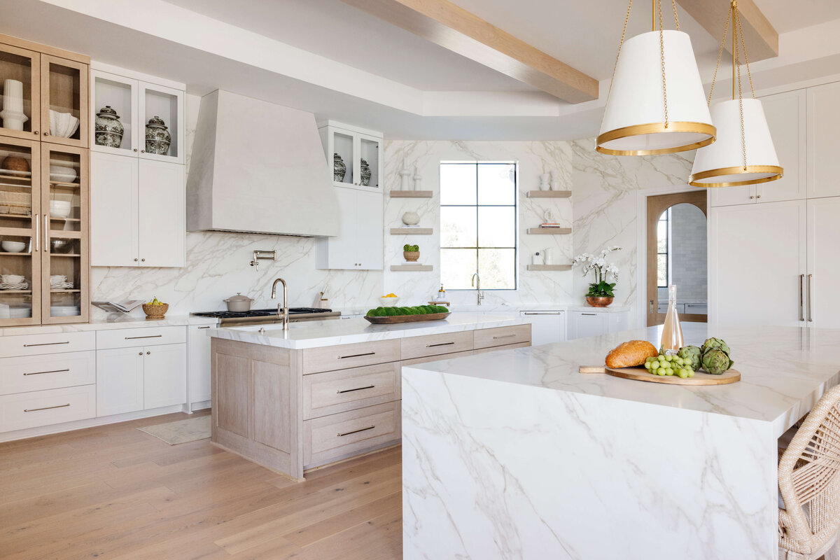 oyster creek studios hughes marble wall and light blue counters white cabinets in kitchen