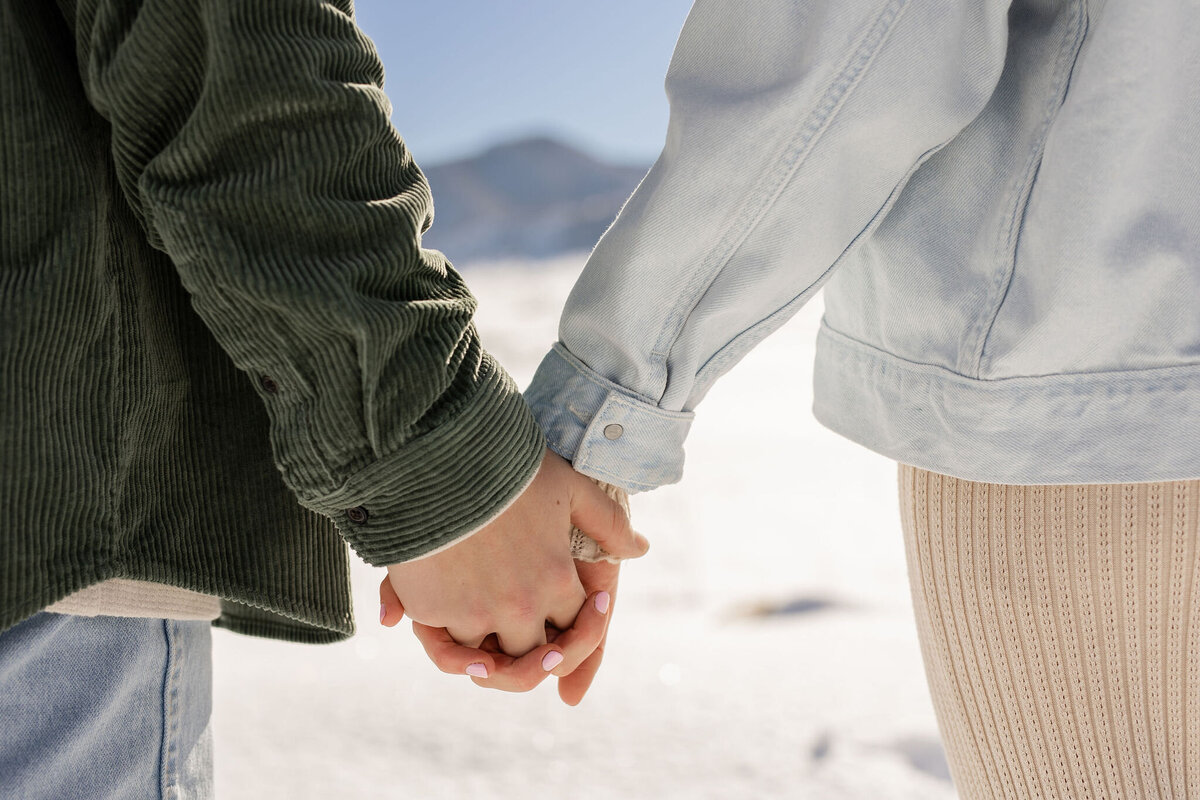 close up of couple holding hands in winter
