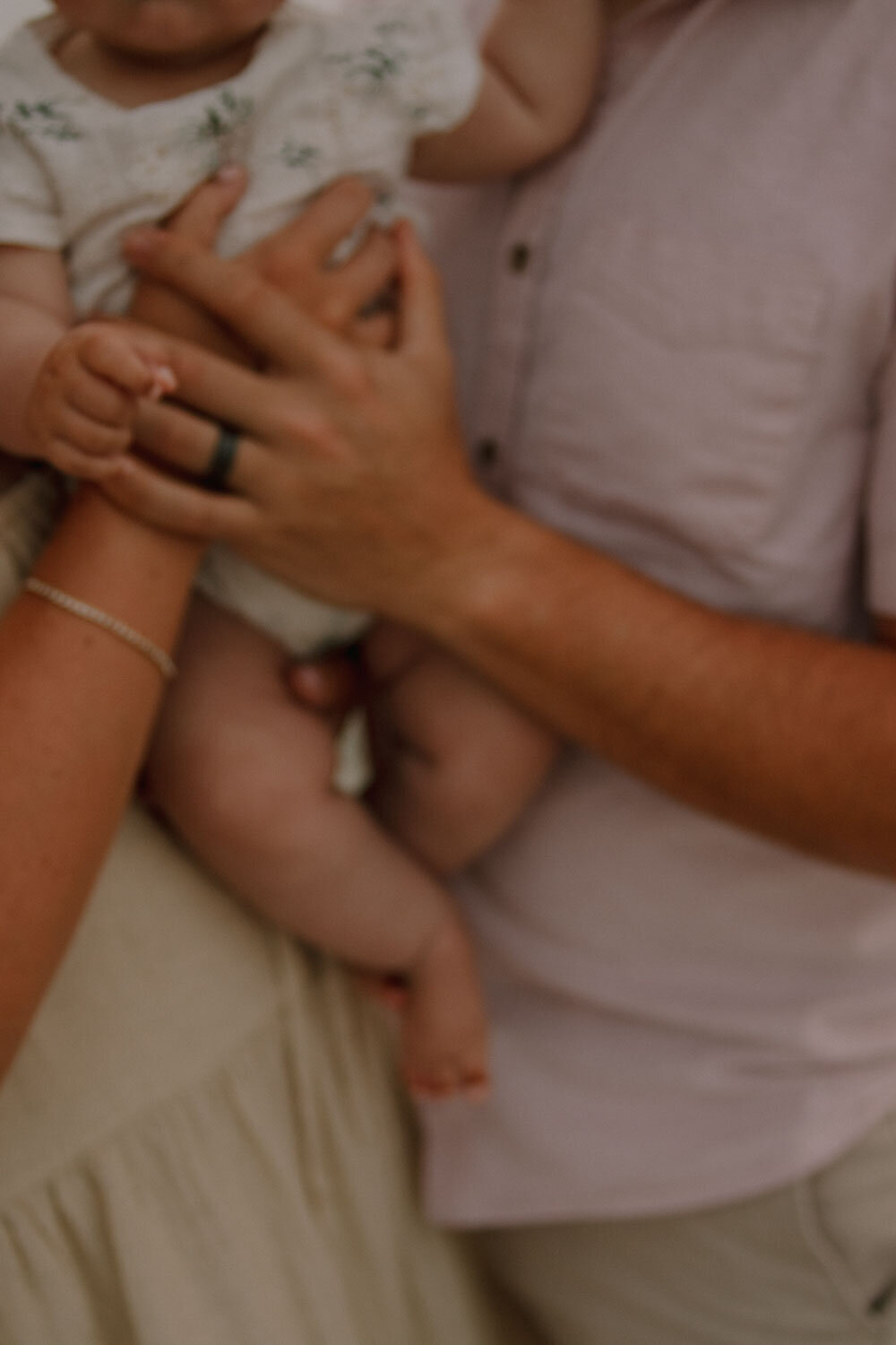 Hands holding a baby, focusing on family bond