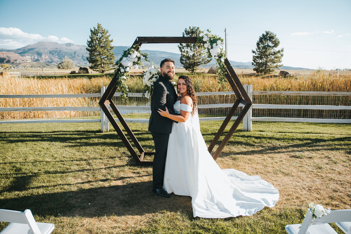 Couple at a hexagon ceremony arch on the lawn