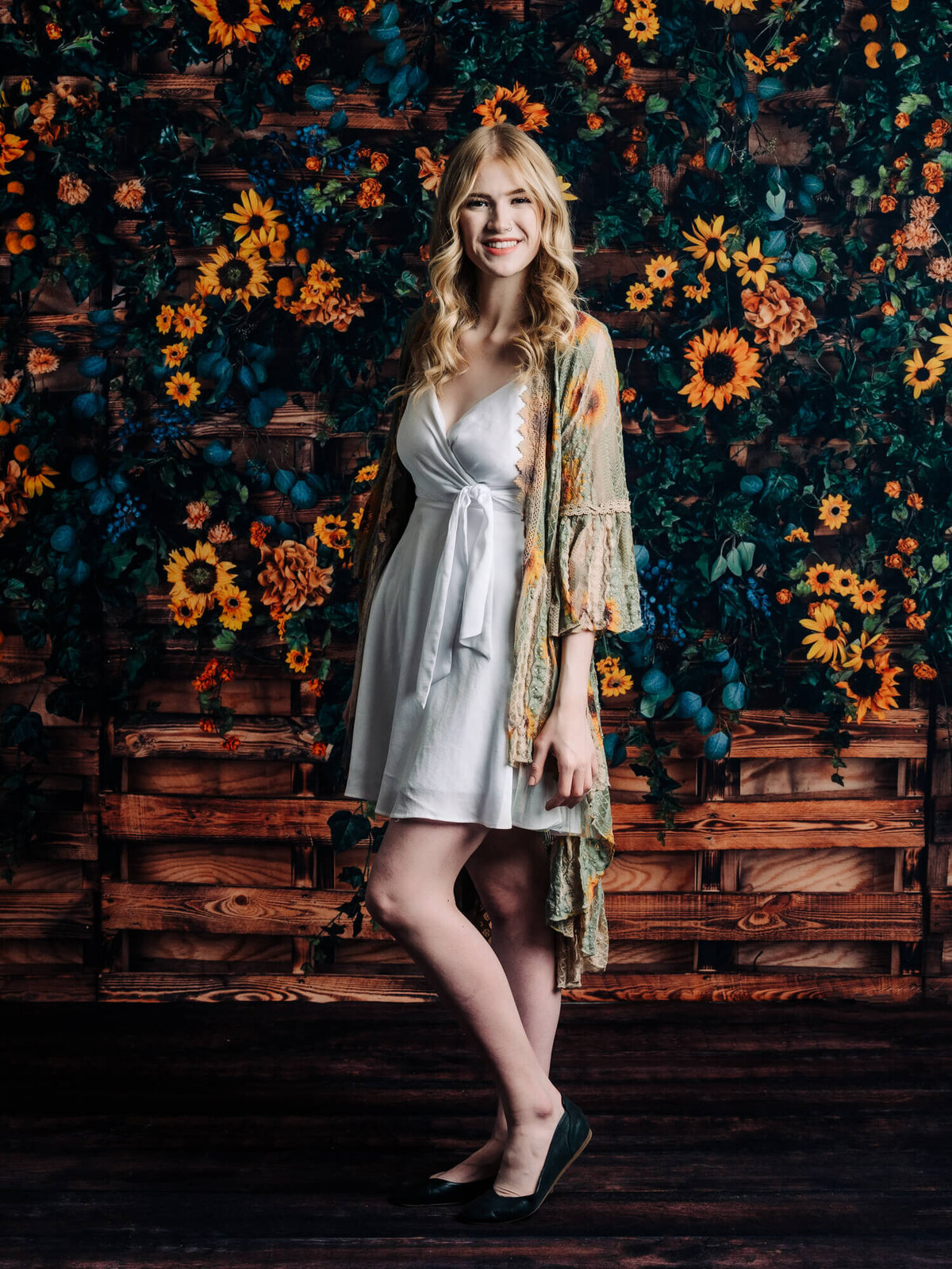 Girl poses in front of sunflowers on pallets in Prescott senior photography session