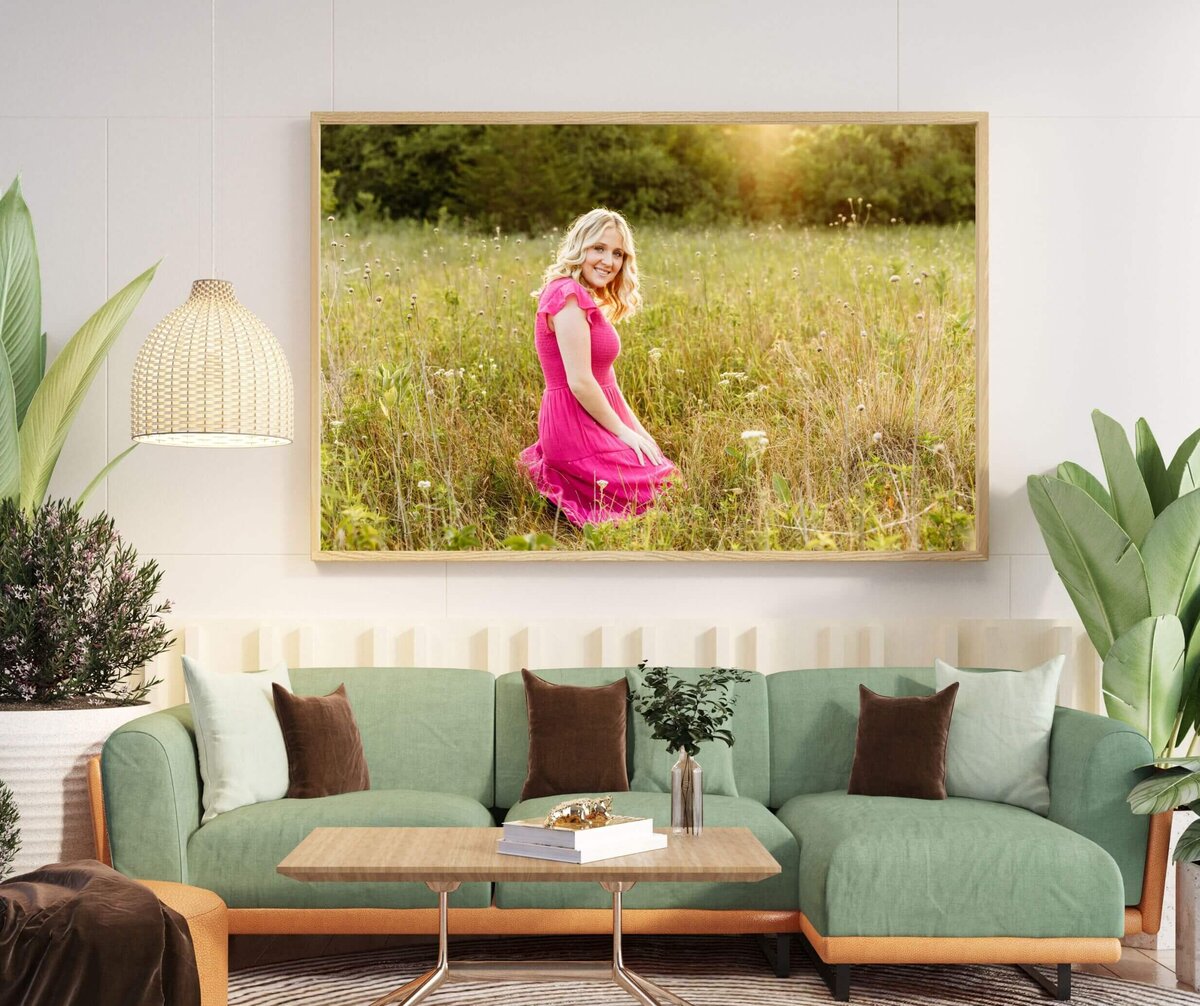 gorgeous photo of a high school senior in a pink dress hanging above a light green couch in a light and airy living room