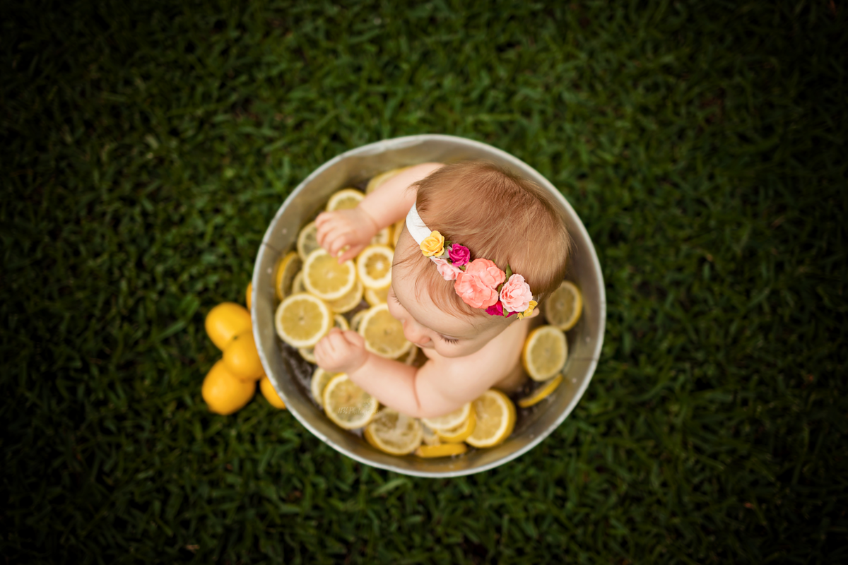 kid in washtub filled with lemons wears floral crown at 6 month milestone sitter photography session
