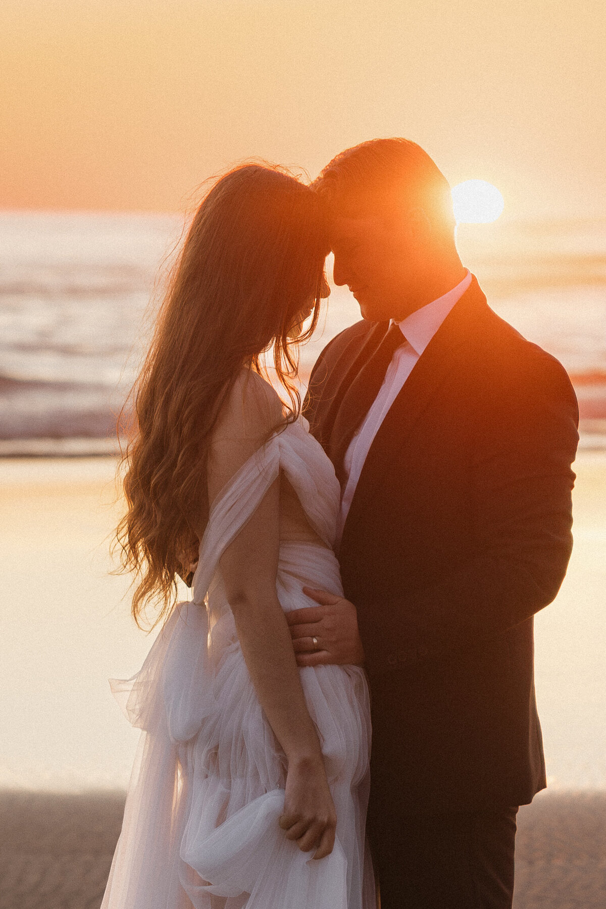 Intimate sunset moment with bride and groom standing on the rocks at Hug Point, Oregon