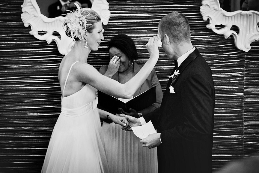 Bride wiping tears from groom during ceremony