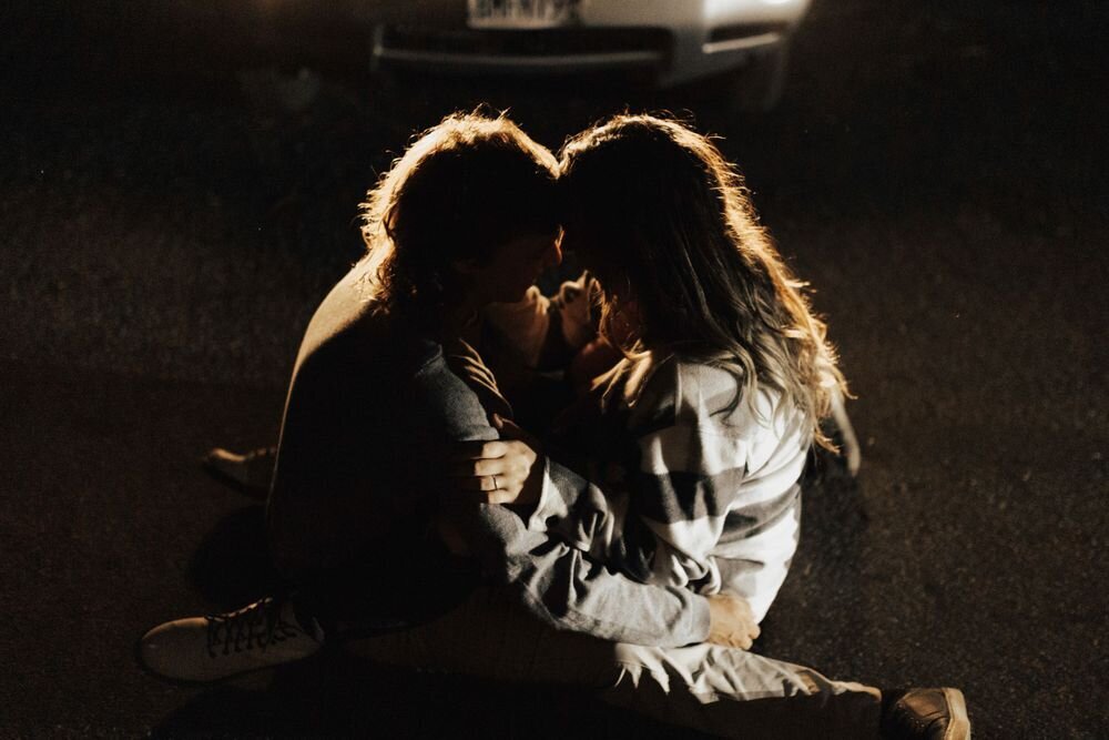 guy and girl cuddling in front of car lights in south lake tahoe during couples session at night