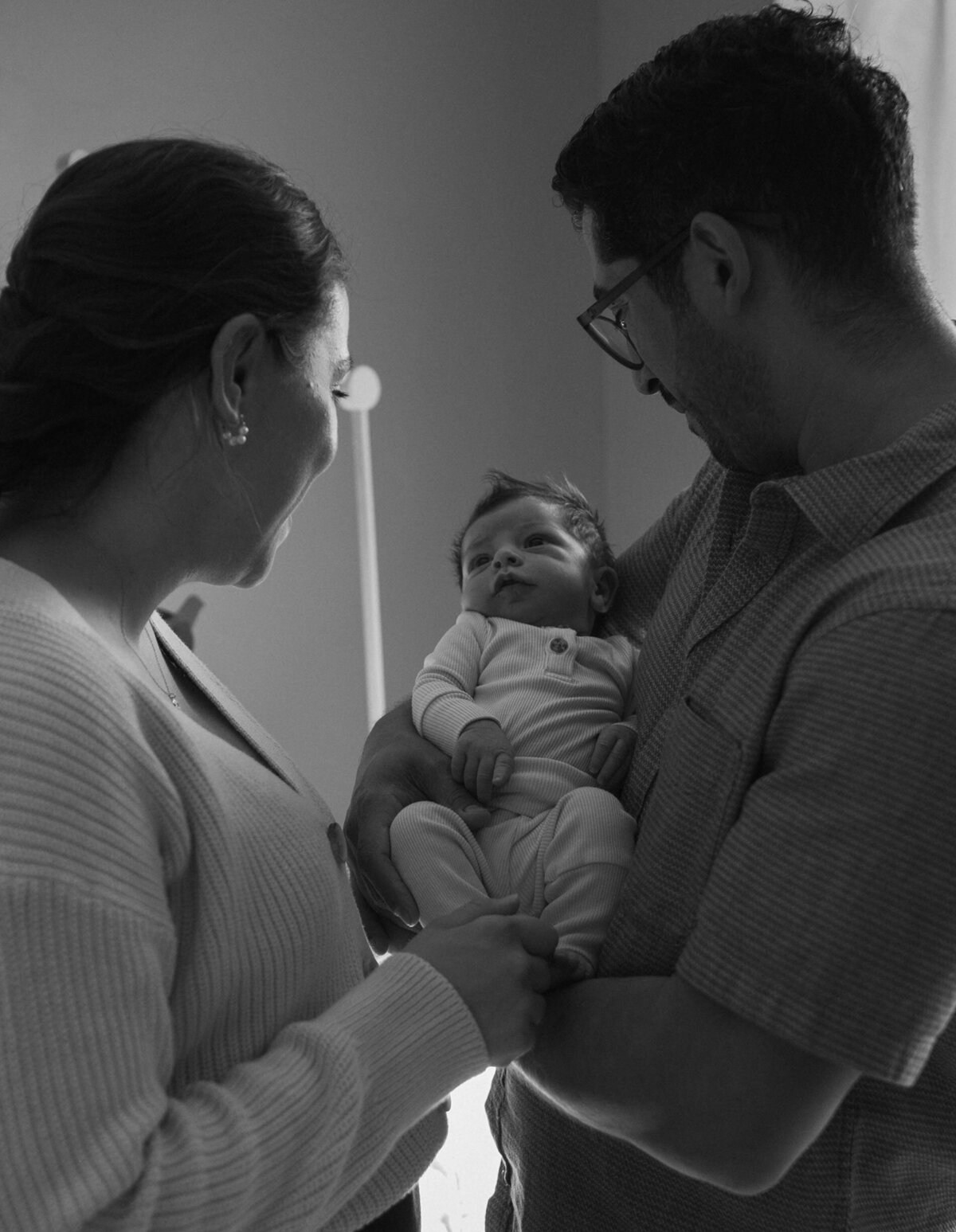 New parents holding and looking down at their newborn baby in awe 