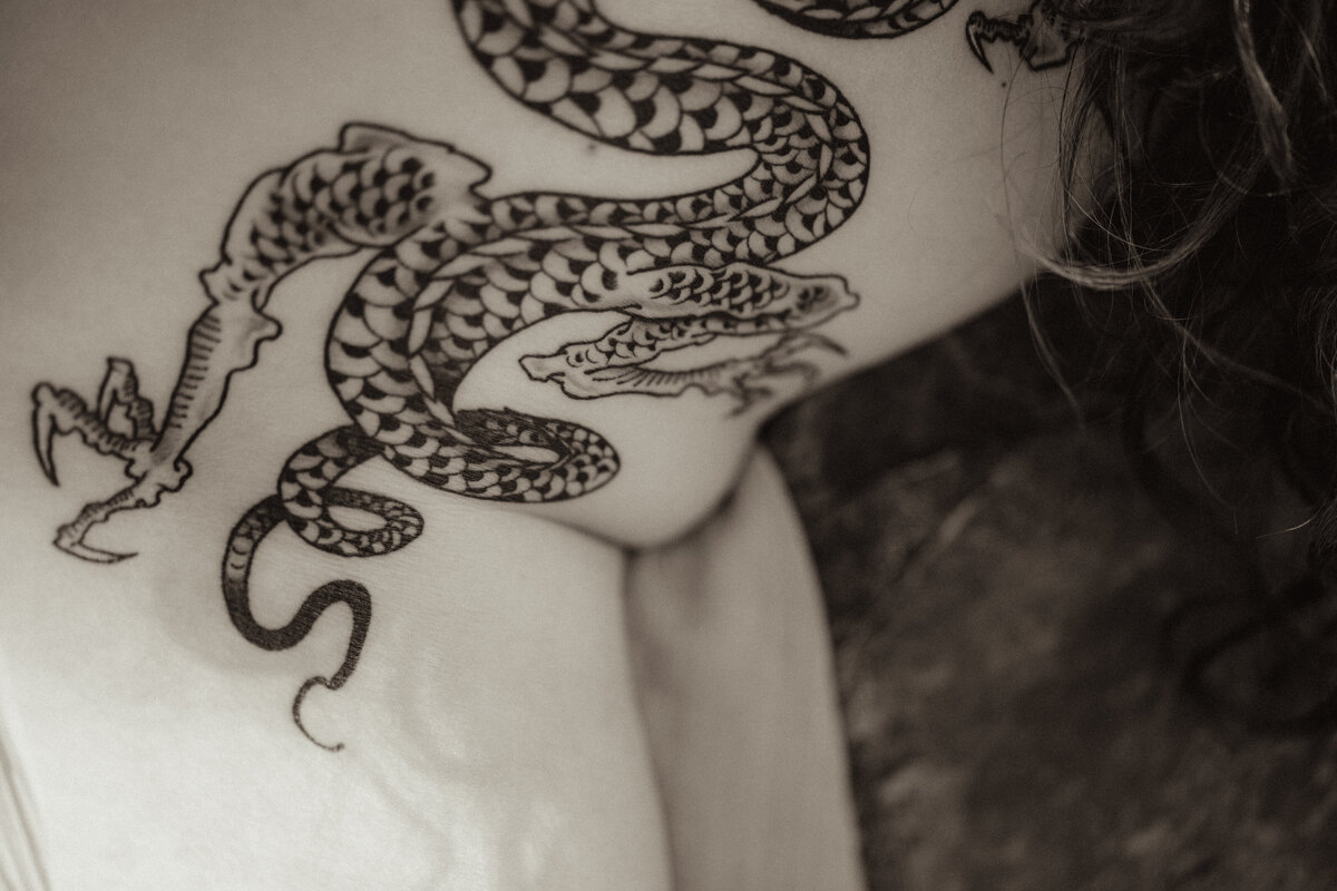 Fine art nude of a woman with a dragon tattooed on her back for a self love session.