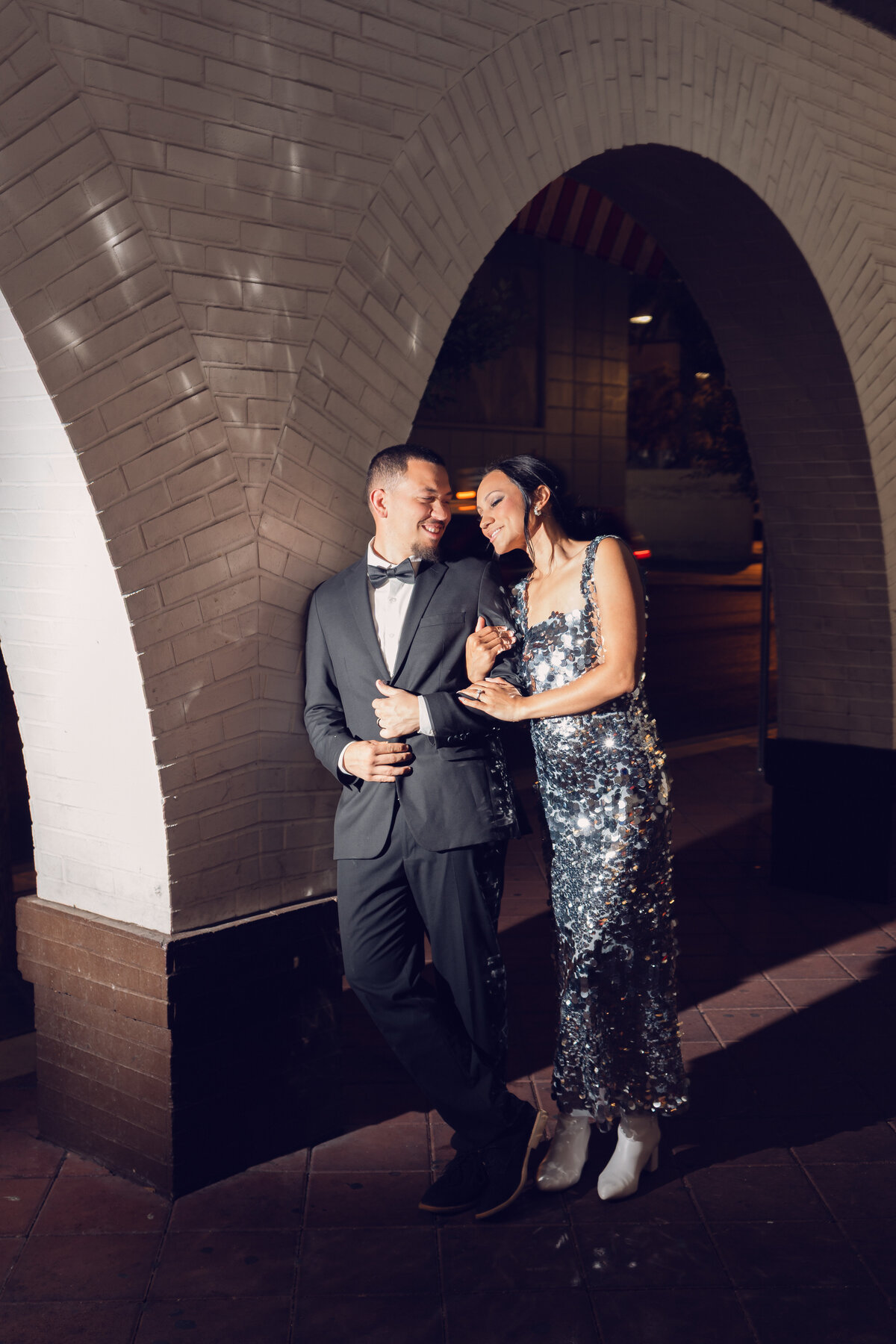 Eloped couple in Las Vegas during night time in an alleyway embracing while her sequin dress lights up the walls