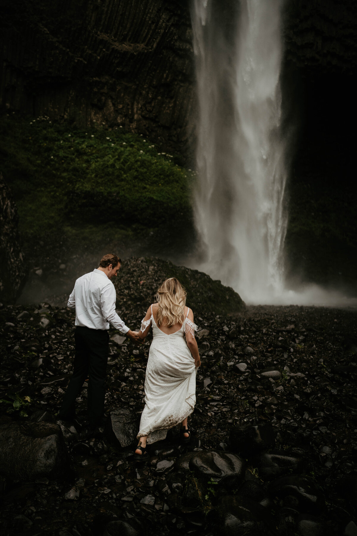 Couple hiking up to waterfall after elopement
