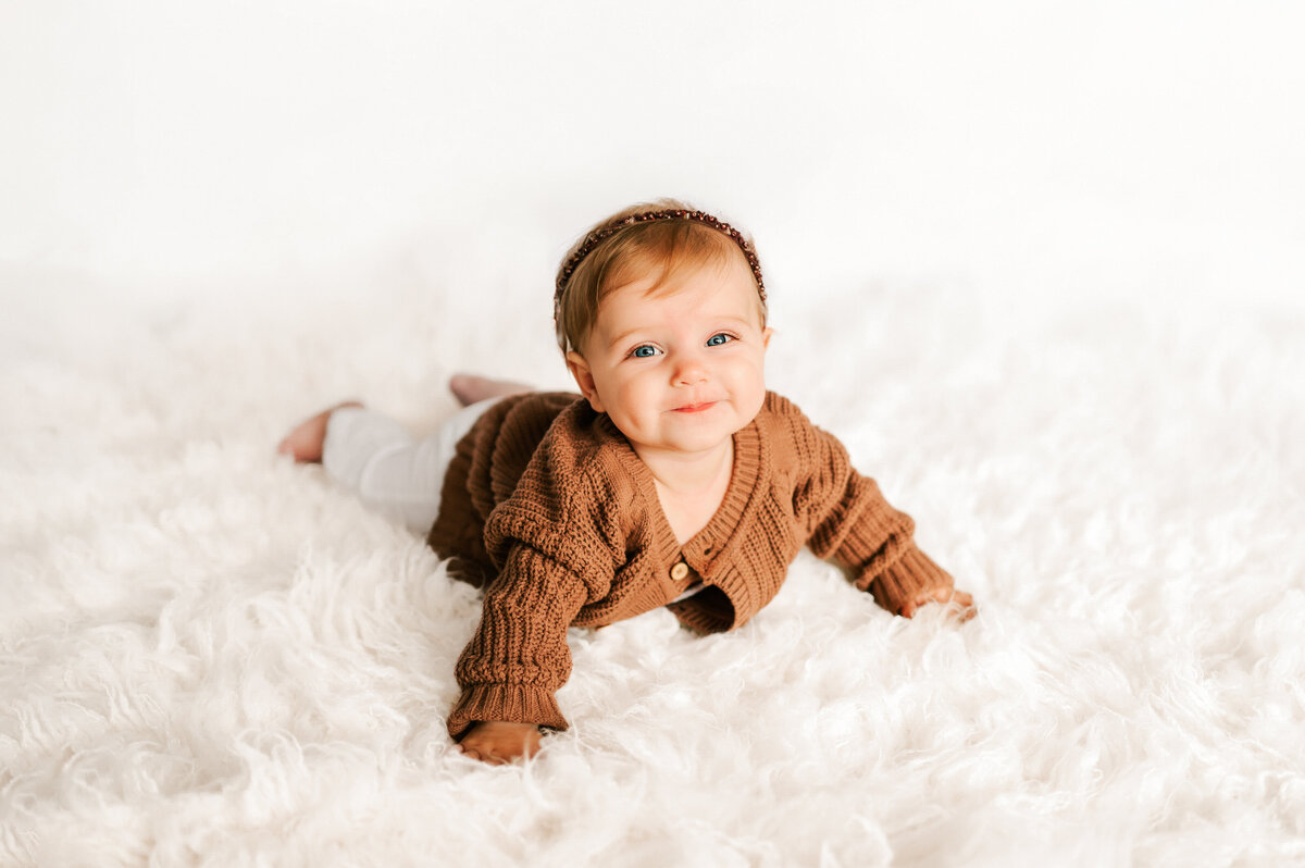 girl laying on rug smiling in Springfield Mo milestone and kids photography studio