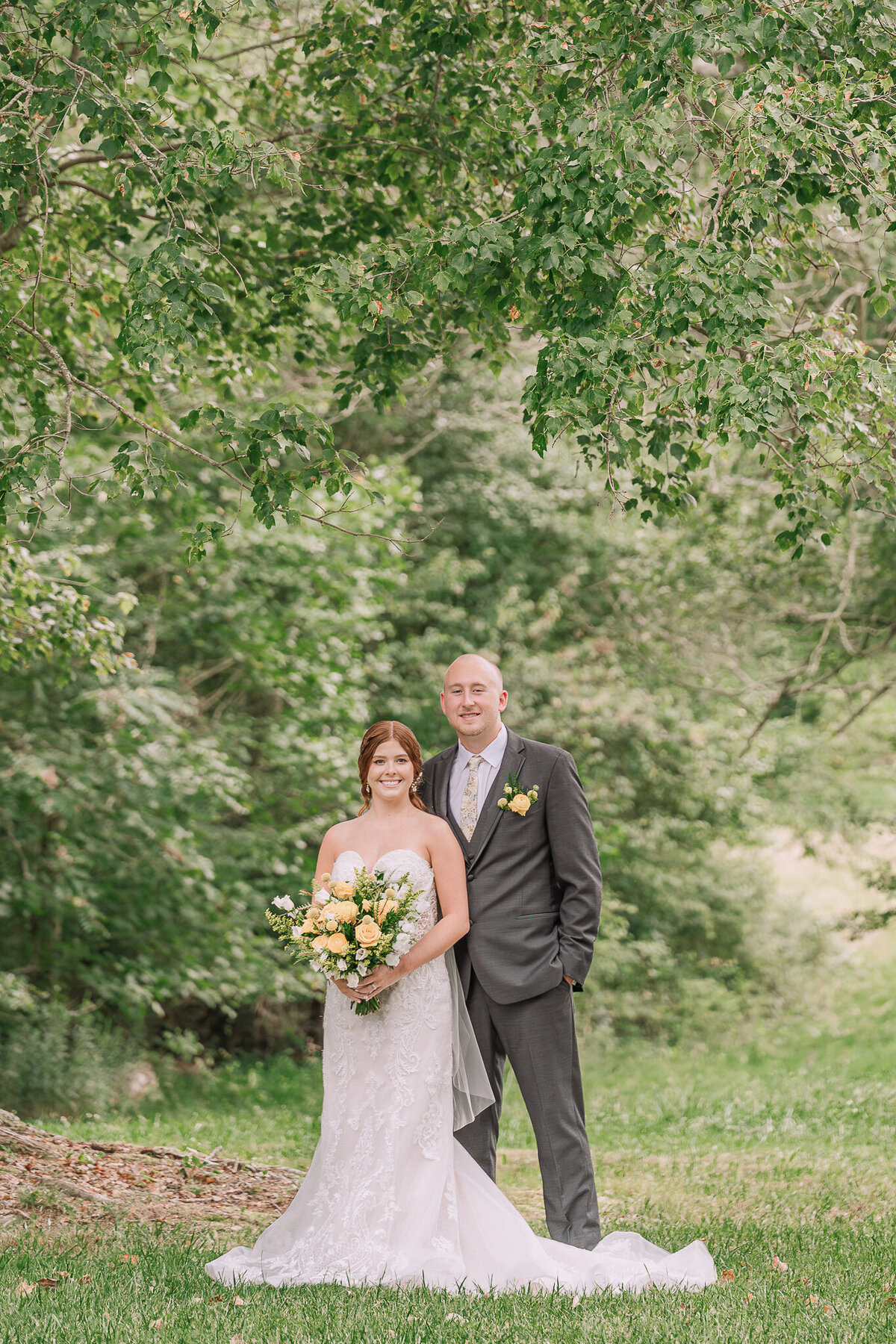 A redheaded bride and her new husband smiling at the camera during their portrait session with JoLynn Photography
