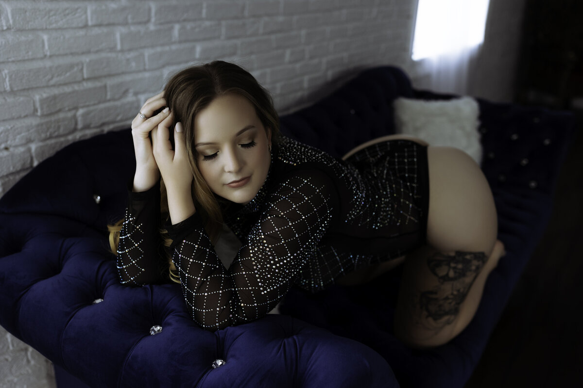 Boudoir Photographer,  a woman kneels on a velvet blue couch
