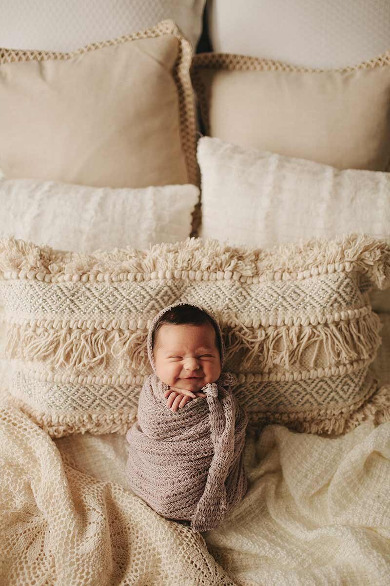 Baby smiling wrapped in blankets for newborn photography