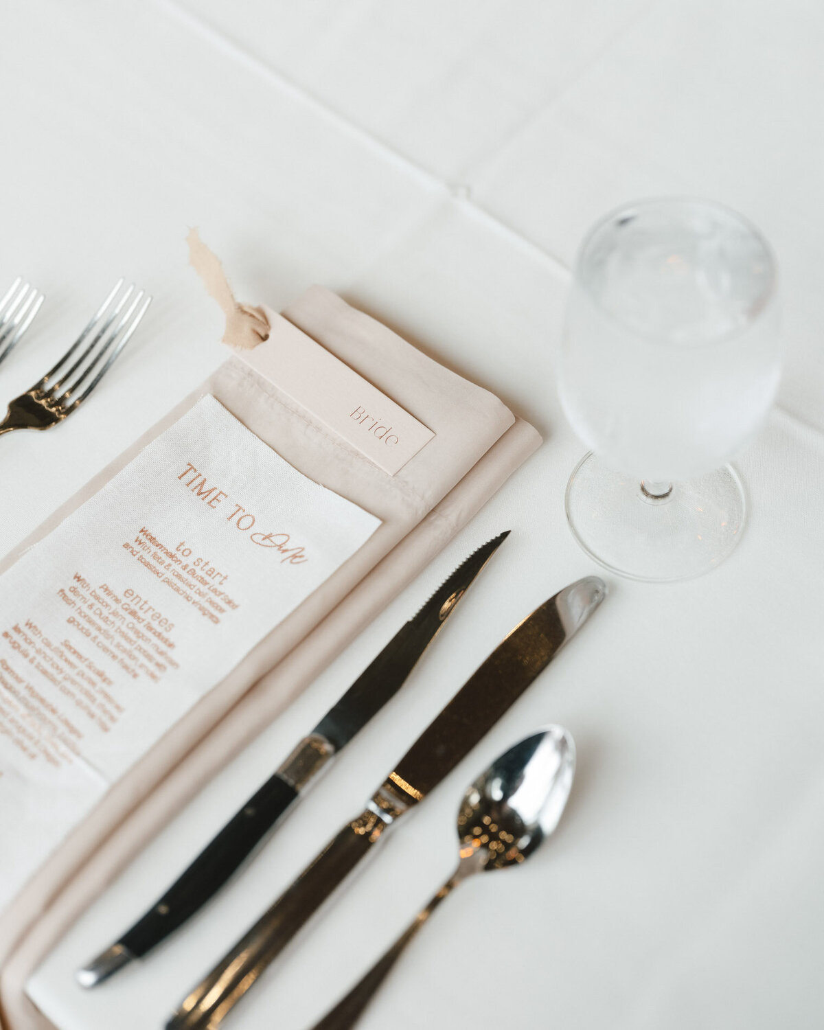 custom calligraphy wedding menu with flatware placed on a napkin on a wedding tablesetting representing full service design and calligraphy by Life in Letters.