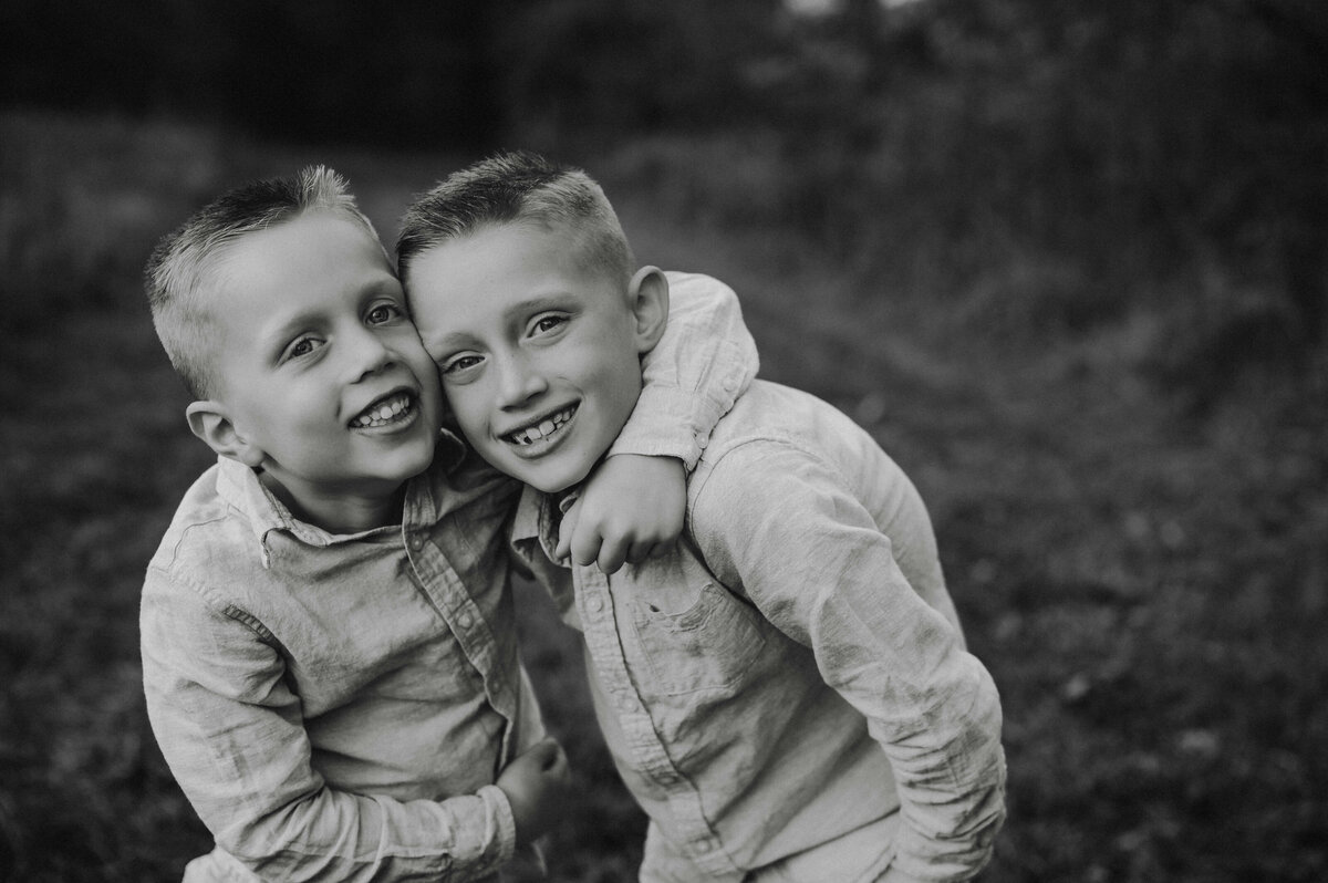 Two young brothers, hugging and smiling in a field 