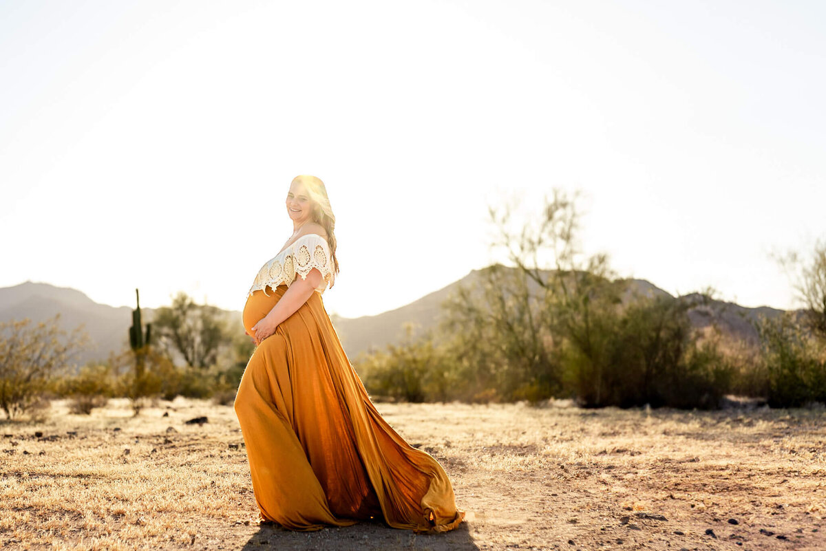 Beautiful pregnant mother in flowing, bohemian dress in the Arizona desert. Captured by Cactus & Pine Photography
