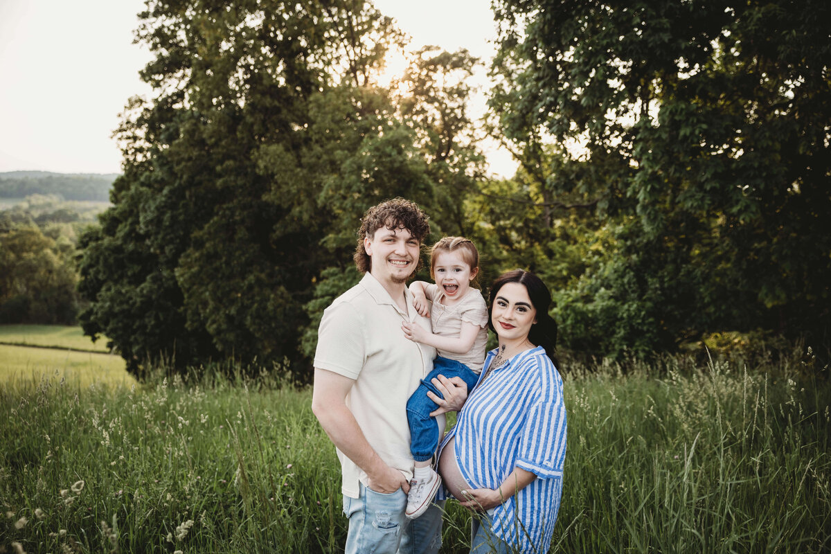 family standing in tall grass smiling in portrait session with reva davis photography