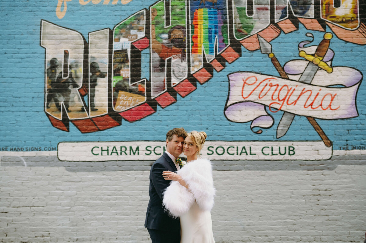 downtown Richmond wedding with bride and groom posing in front of a wall mural on a building for their winter wedding