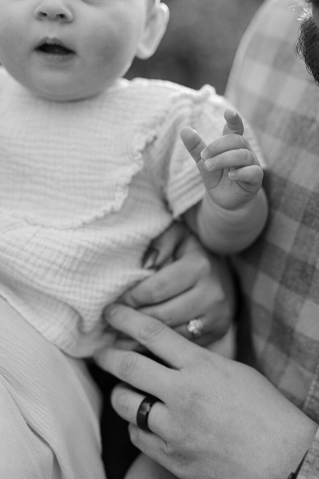 Close up of mother and father hands holding a baby