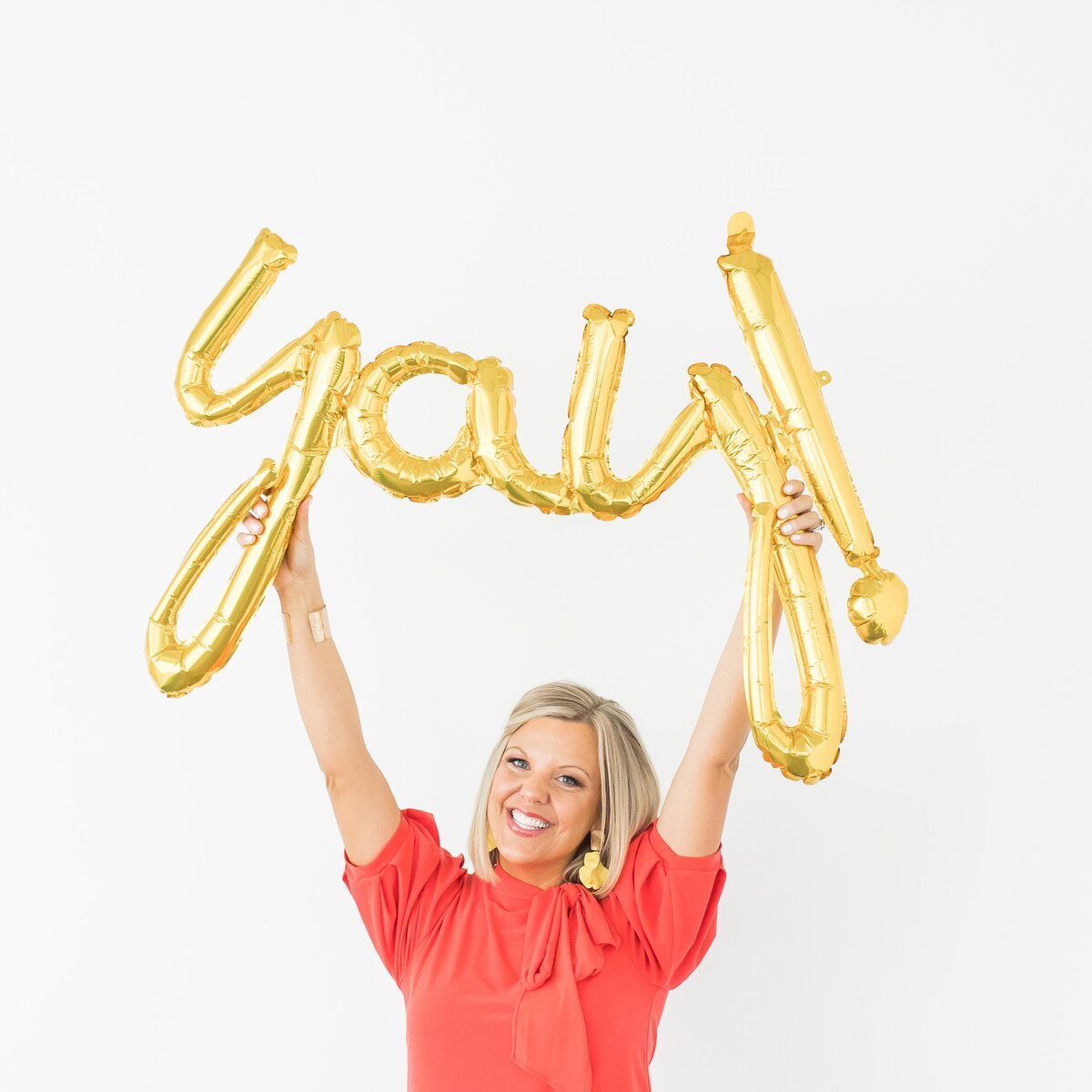 a woman holding up balloons that spell the word yay