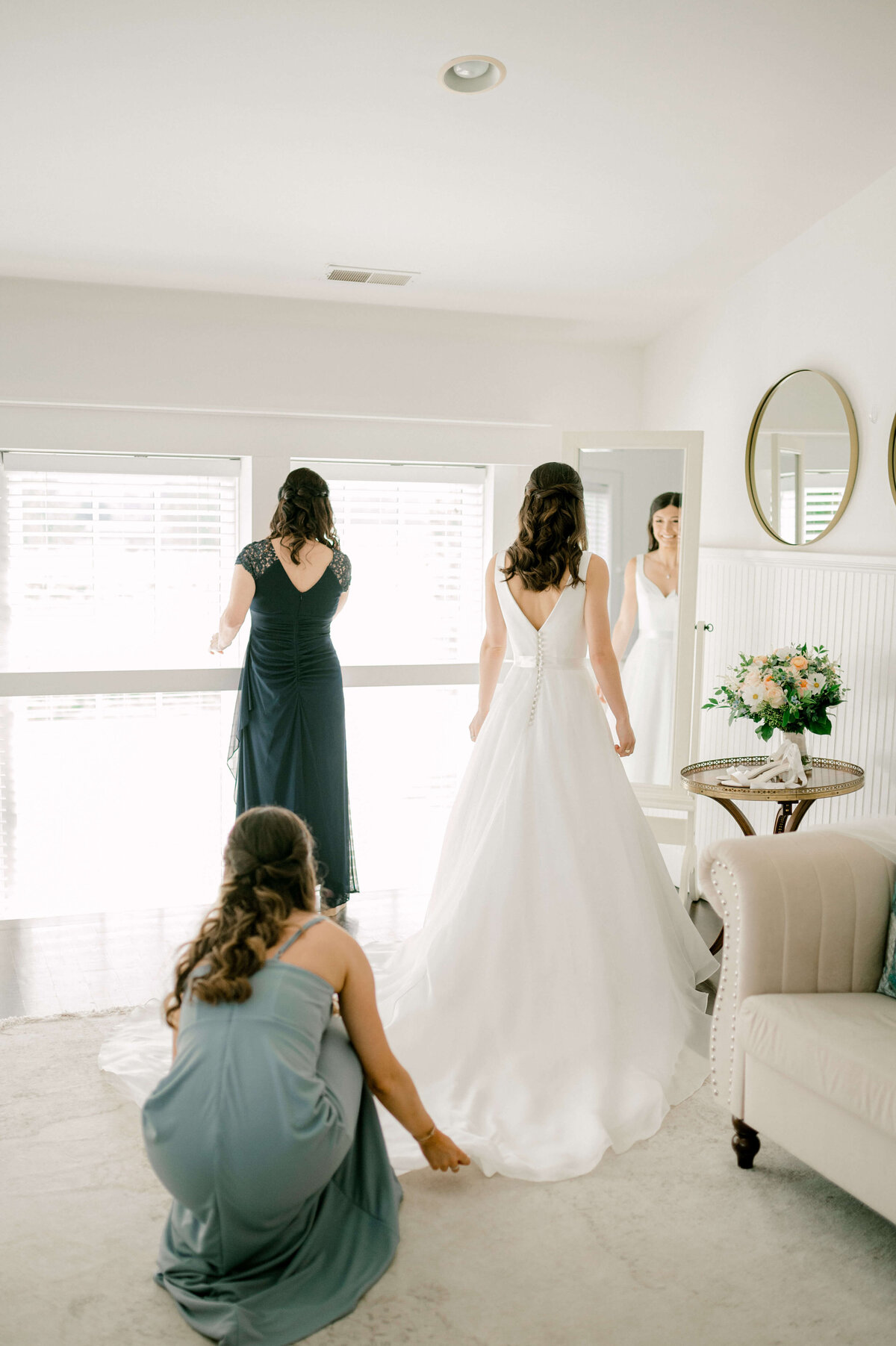 Bride getting ready woth her mother and sister as they help her get dressed in a DC bridal suite.