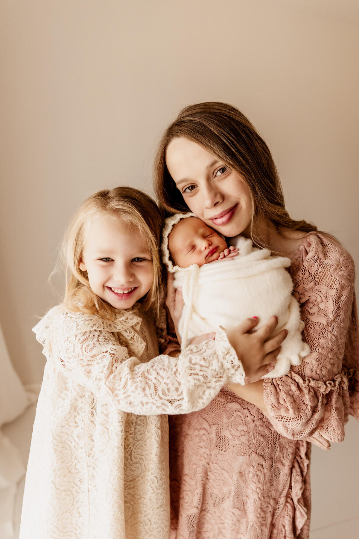 Mother wearing a pink lace dress next to her two daughters.