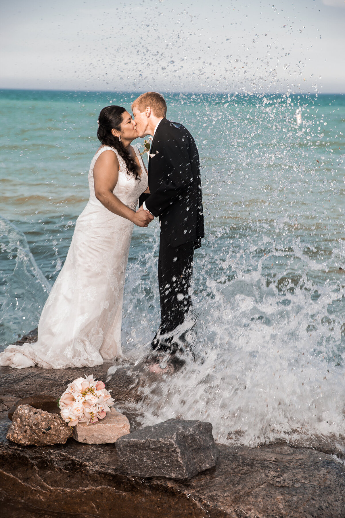 A beach wedding portrait taken on the rocks at a Lake Michigan