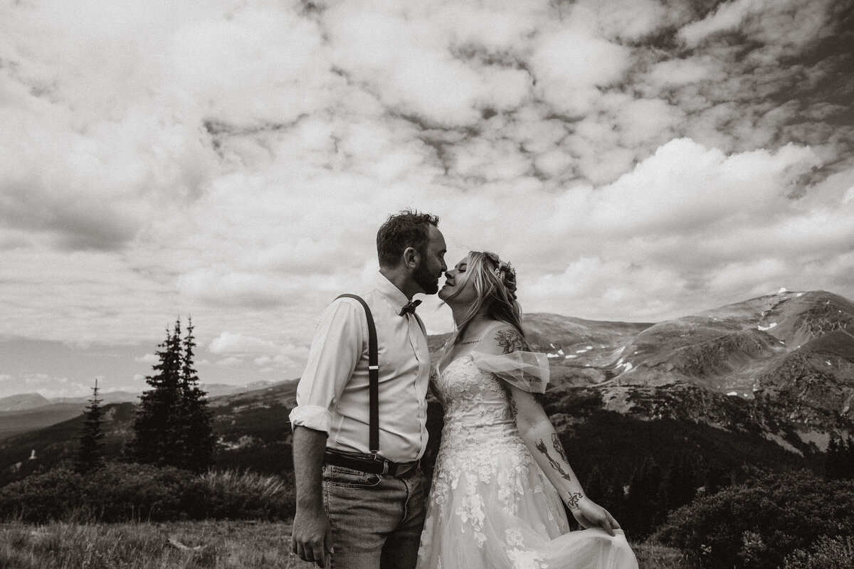 Bride and groom kiss under dramatic skies with Colorado mountain peaks behind them in Hoosier Pass.