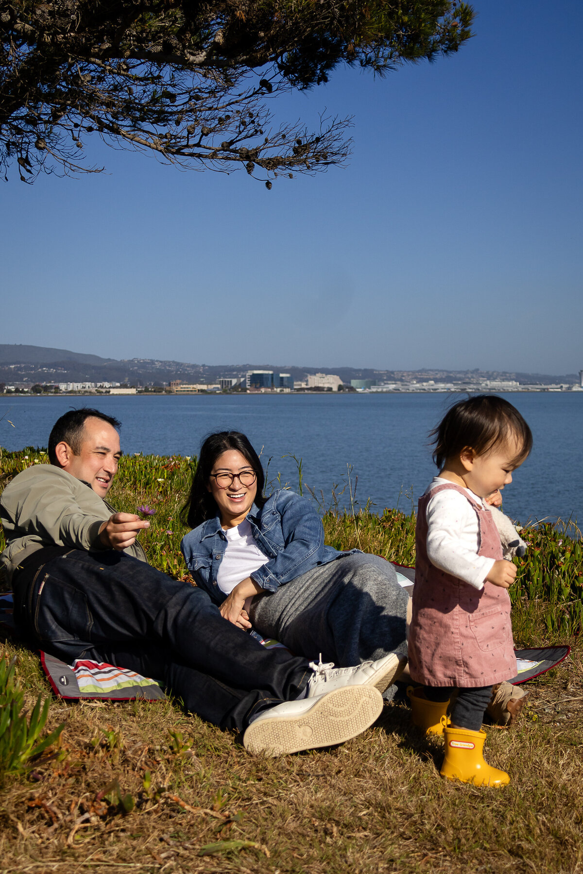 Candid moment of parents and toddler bonding by the San Francisco Bay – natural light family photography by Ellobelle Photography, San Francisco Peninsula Bay Trail Burlingame