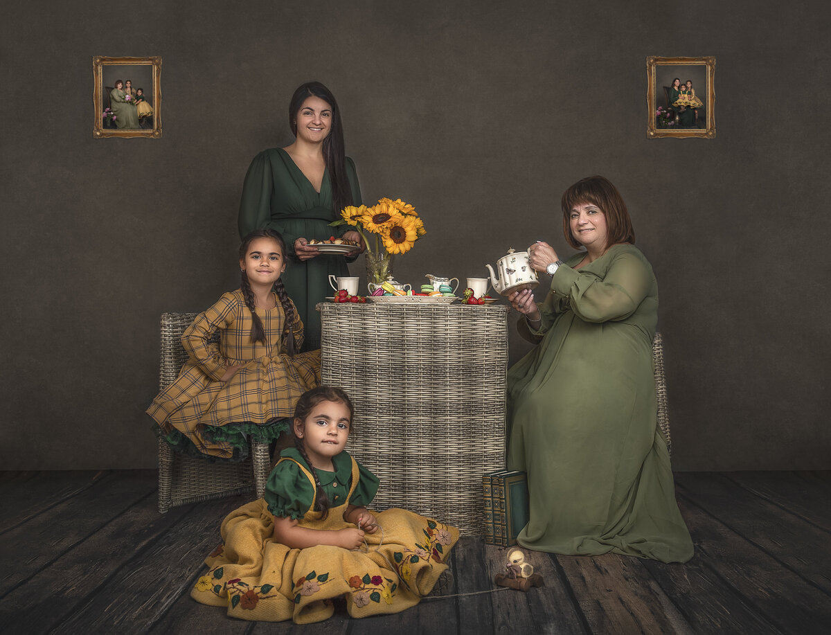 A family of four girls sit and stand around a table that has tea and flowers on it.  Phot taken by Sonia Gourlie.