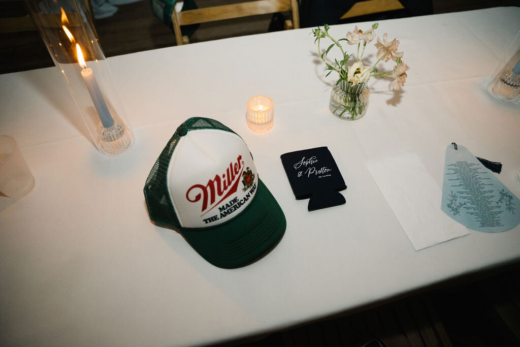 Custom wedding reception hat and koozie on a reception table