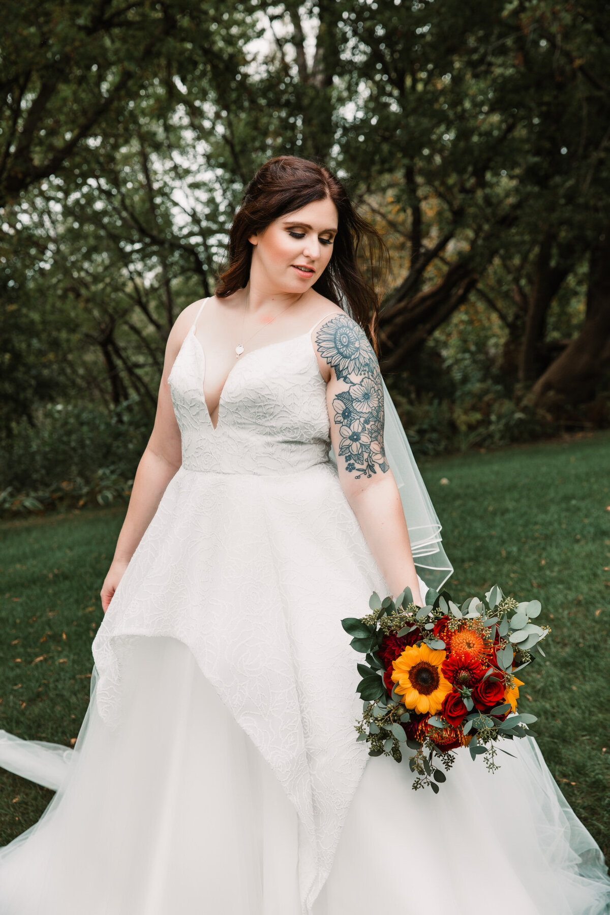 bride poses with flowers at her side and her ball gown dress