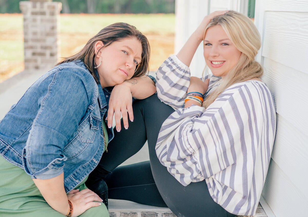 Sisters sitting on back porch leaning on each other during their fall sister's photo shoot in portal Georgia