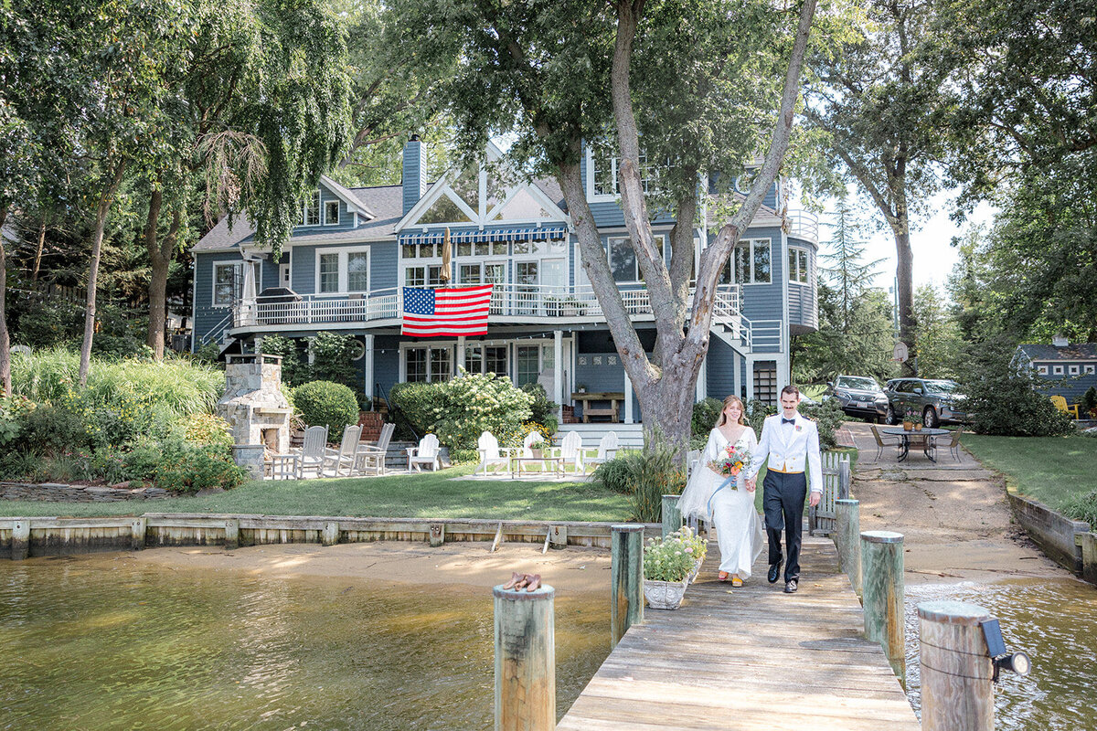 Bride and groom walking on dock with american flag in background