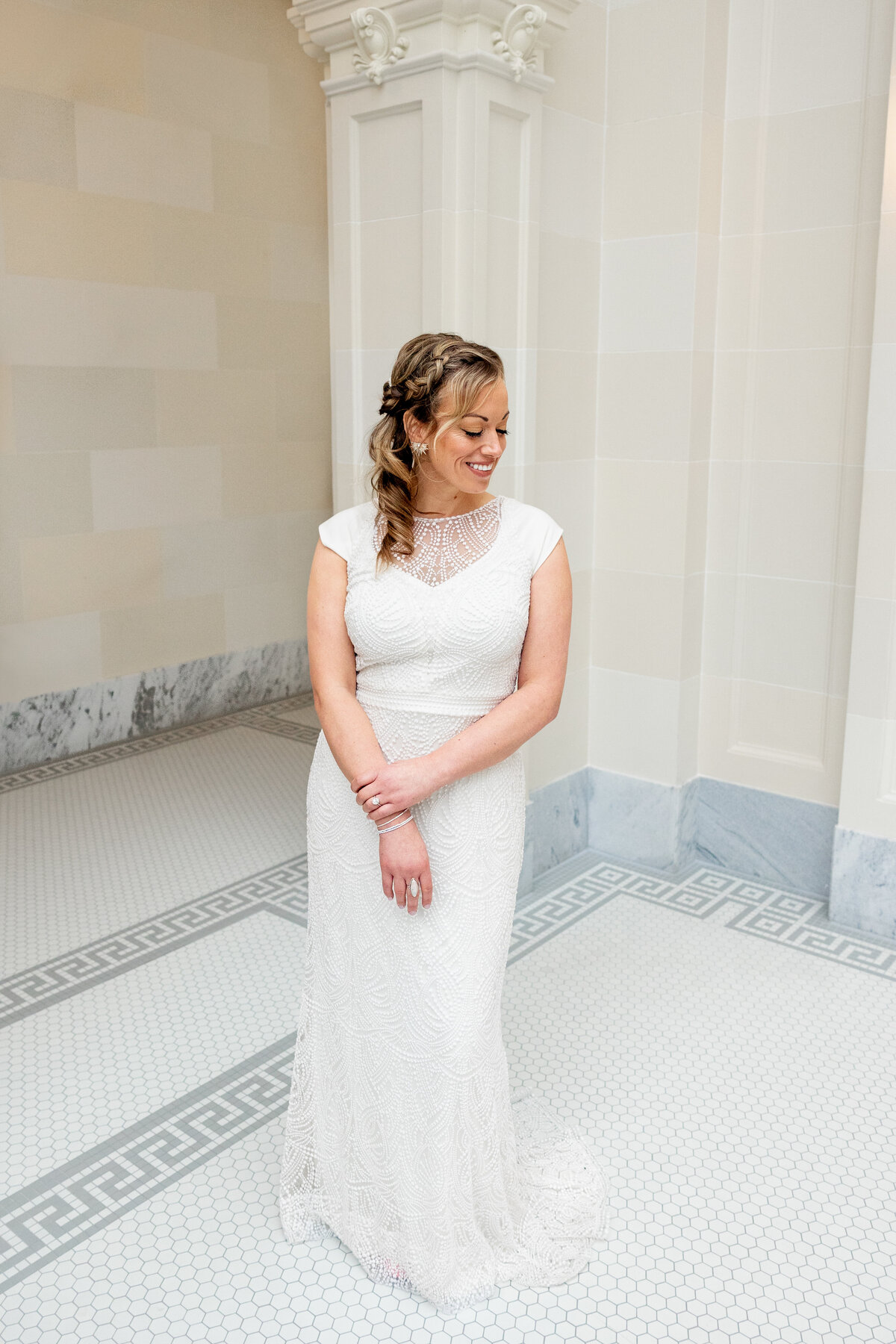  The bride poses with a radiant smile in a detailed lace wedding gown inside the Utah State Capitol.