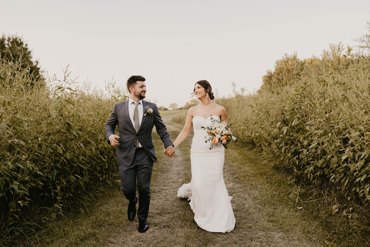 Bride and groom running running in a field. 