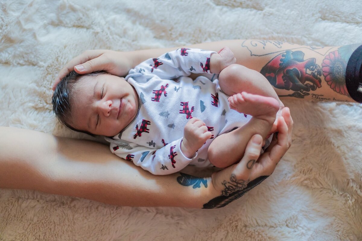 tattooed arms holding baby
