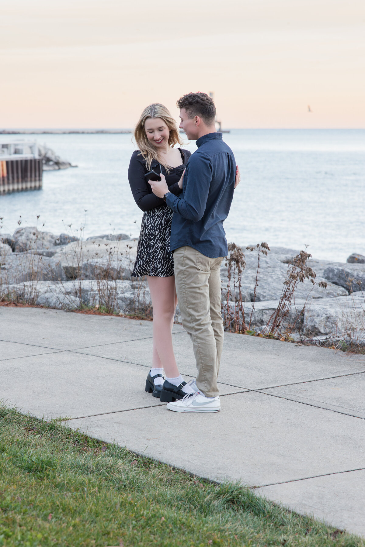 Engaged couple hugging and looking at the ring in the box