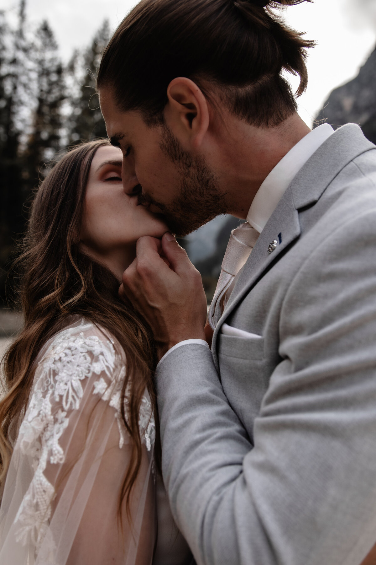 Elopement wedding couple posing on a cliffside with dramatic mountain views